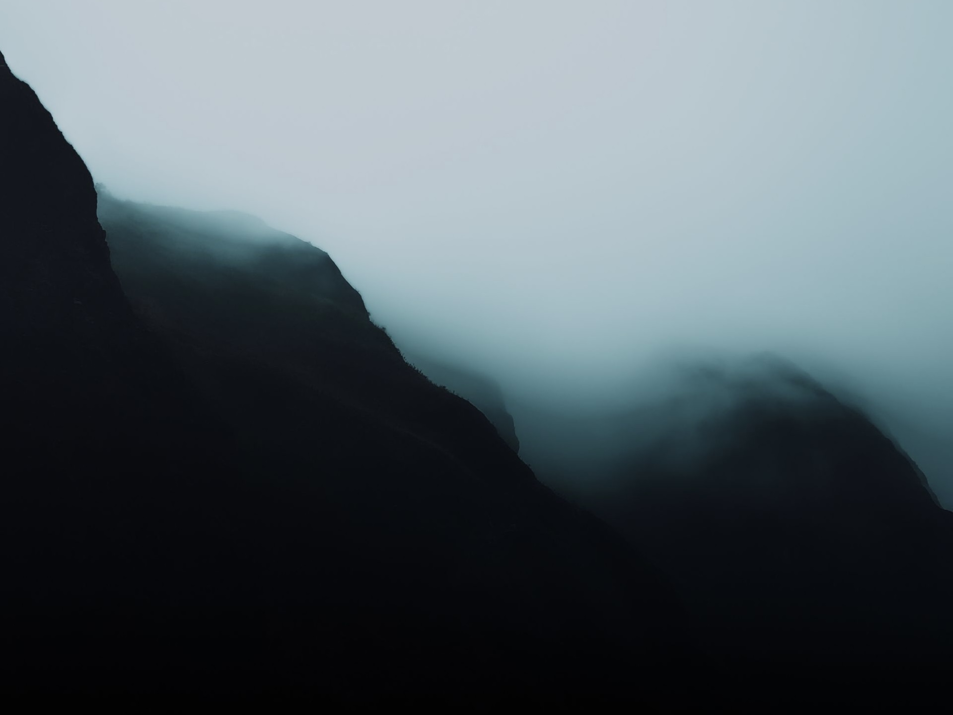 A dark mountain ridge emerging from heavy fog, used to represent content structure taking shape out of scattered publishing